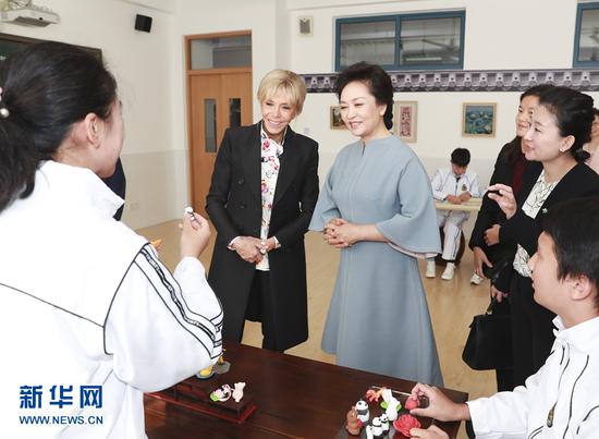 11月5日，国家大大平夫人彭丽媛邀请法国总统夫人布丽吉特共同参观上海外国语大学附属外国语学校。这是彭丽媛和布丽吉特在中国非物质文化遗产课堂观看学生们学习面塑制作。新华社记者 丁林 摄