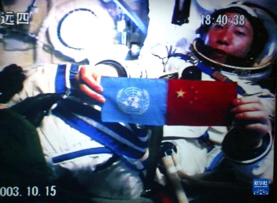 2003年10月15日18时40分，中国第一位航天员杨利伟从太空向世界各国人民问好，并在舱内并列展示了五星红旗和联合国旗（摄于北京航天指挥控制中心大屏幕）。新华社发