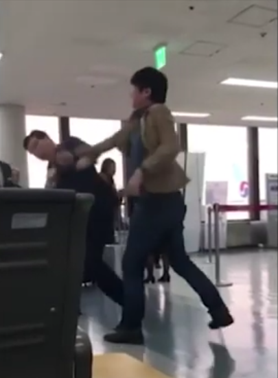 武田（黄色外套男子）出拳打向机场工作人员（FNN新闻报道截图）