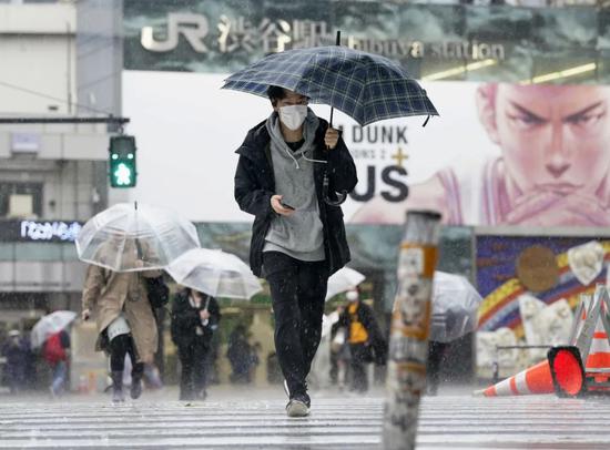 4月18日，在日本东京，行人戴口罩走在涩谷街头。新华社/共同社
