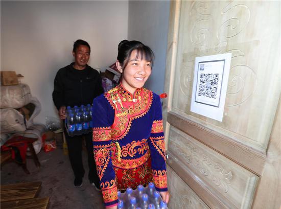  吉好也求的大女儿吉好有作在四川昭觉县三岔河乡三河村新居小卖部里搬饮料（2019年2月11日摄）。新华社记者 江宏景 摄