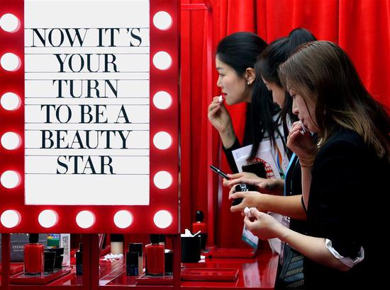 11月6日，在第二届进博会品质生活展区，观众在欧莱雅旗下品牌彩妆展台试用口红。 新华社记者刘颖摄