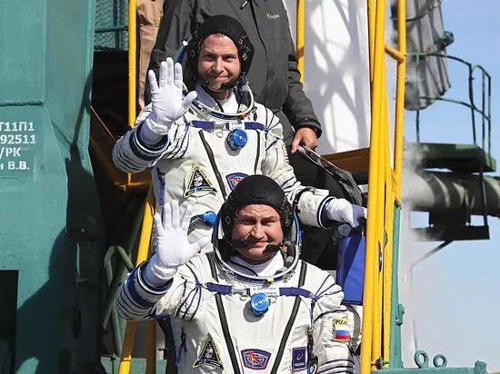  10月11日，在哈萨克斯坦拜科努尔发射场，两名航天员登上载人飞船。（新华/法新）