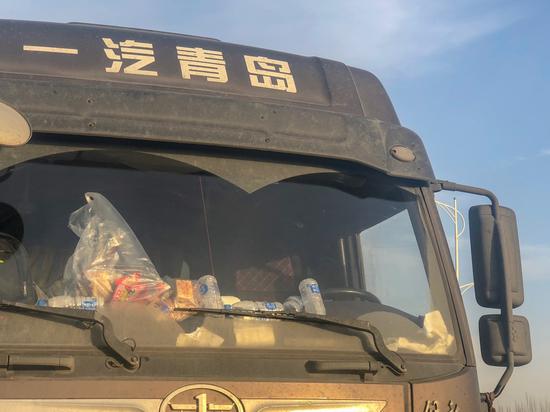 11月28日下午5点货车司机放在窗前装着矿泉水、榨菜和沙琪玛的零食袋。实习生侯轶 摄