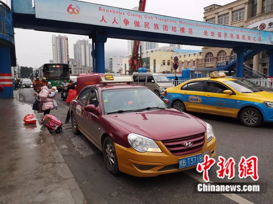 2月13日，民众在柳州市汽车南站打车，司机下车帮忙搬运行李。