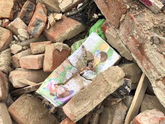 废墟中，小龙的语文书被土掩盖。新京报记者解蕾 摄