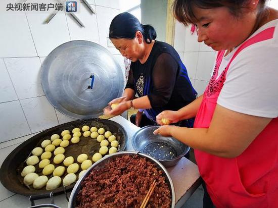 △张国利老伴和儿媳正在做粘豆包。（央视记者荆伟拍摄）