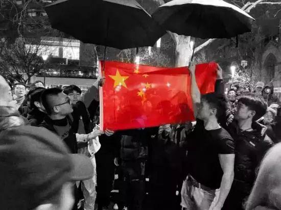 ▲中国留学生自发赶来，将乱港分子团团围住，他们高唱国歌，在雨夜中为国旗撑伞，手机/平板的屏幕上的国旗分外耀眼 （图via网络）