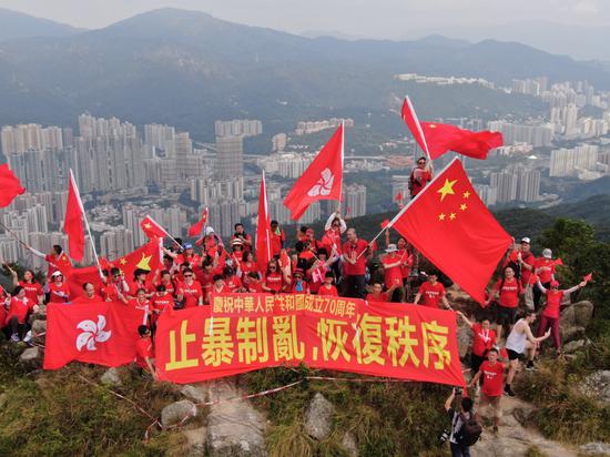 9月14日,百余名香港市民分两批爬上狮子山顶,他们身穿红色T恤,挥舞国旗、区旗,并展示“庆祝中华人民共和国成立70周年”和“止暴制乱,恢复秩序”的横幅。