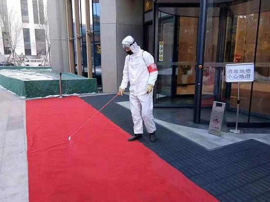 金茂物业的工作人员在对写字楼门前的地垫进行消杀。
