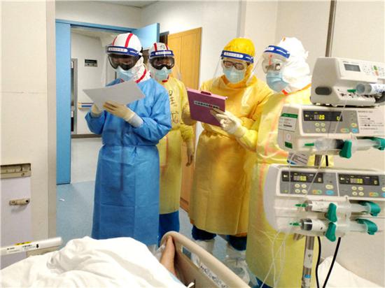 在武汉同济医院中法新城院区ICU病房内，来自北京协和医院的医护人员在病床旁查房交班（2月11日摄）。北京协和医院驰援武汉的135人护理团队中，八成是女同志。新华社发