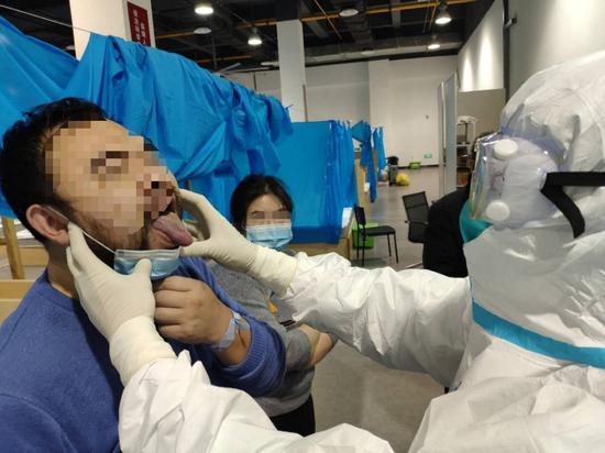 刘清泉在方舱内最后一次查房。患者取下口罩,让他查看舌苔。 摄/新京报记者 戴轩