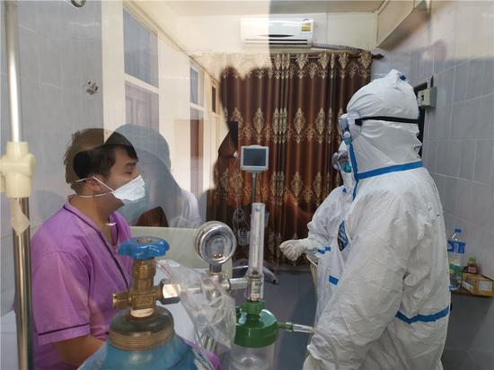 4月4日，在老挝首都万象150医院，中国抗疫医疗专家组成员（右）探访老挝新冠肺炎患者。新华社发（中国抗疫医疗专家组供图）