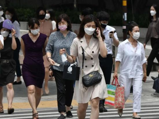 ▲6月23日，戴口罩的行人在韩国首尔市中心过马路。（新华社/法新）