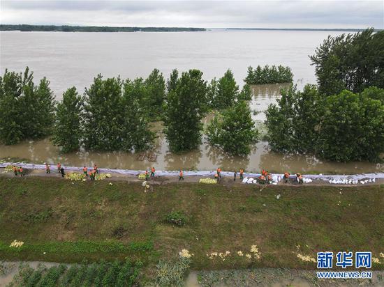 7月16日，在安徽无为长江大堤外护圩三垄圩段，武警官兵用沙袋加固子埂（无人机照片）。 新华社记者 周牧 摄