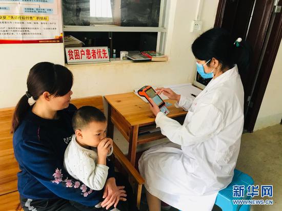广西乐业县新化镇百坭村群众通过“村医通”系统现场进行医疗费用结算(2020年2月12日摄)。新华社发(广西壮族自治区医疗保障局供图)