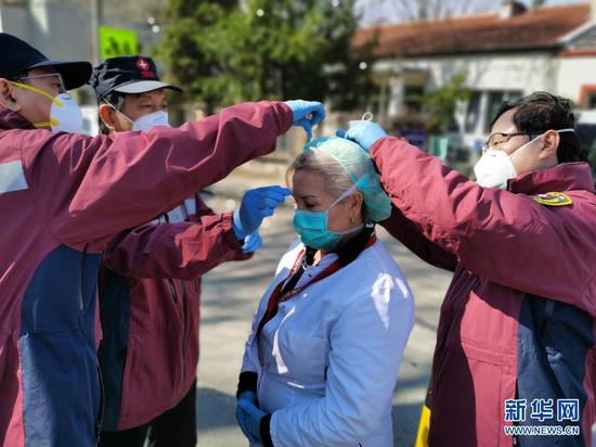 2020年4月4日，中国赴塞尔维亚抗疫医疗专家组在贝尔格莱德的基层发热门诊为门诊主任特里富诺维奇（中）更换防护标准更高的口罩。新华社发