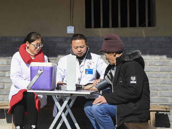 重庆市石柱土家族自治县中益乡卫生院的医护人员为华溪村村民谭登周测量血压（2019年12月10日摄）。新华社记者 王全超 摄