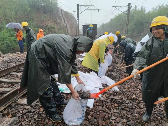 工作人员正冒雨抢修铁路。来源：中国铁路郑州局集团有限公司