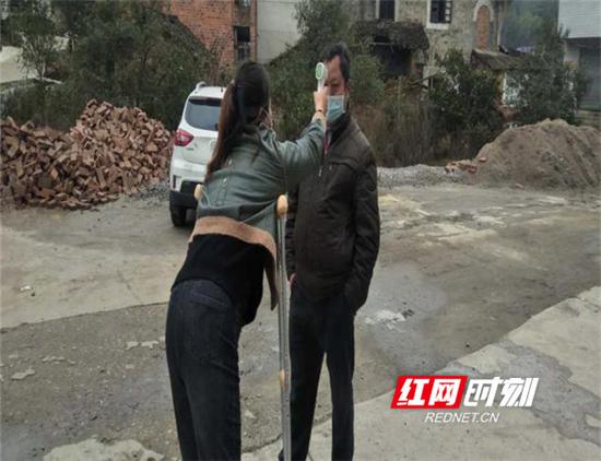 刘利云受伤后拄着拐杖为返乡人员测体温。