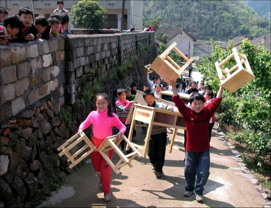  2003年5月，浙江省桐庐县毕铺乡百岁村希望小学，学生们搬运爱心企业刚刚捐赠的桌椅。