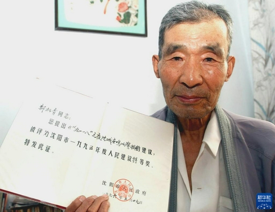 沈阳市民郝松青在展示自己“9月18日鸣响警报的建议”获得当年人民建议特等奖证书（2005年9月13日摄）。新华社发