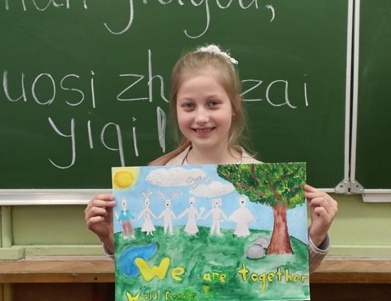 在白俄罗斯首都明斯克，一名小学生展示自己支持中国抗击新冠肺炎疫情的绘画作品。