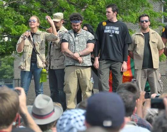  图为2012年5月20日，一名美国老兵（左）在芝加哥举行的反战集会上发表演讲时，准备扔掉美国政府颁发的反恐勋章。图源：新华社张保平摄