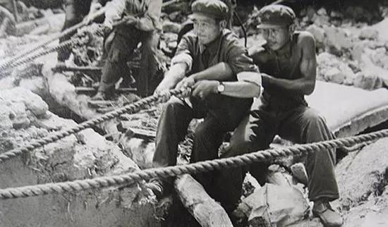 在没有大型起重工具的情况下，解放军战士用双手拨开重物救人