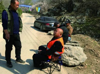 居庸关花海:拍居庸关花海必经路被封 当地人收钱带游客上山 摄影师们到达目的地后,老板(左)与工作人员抽起了香烟,看山员并没有阻止上山拍摄
