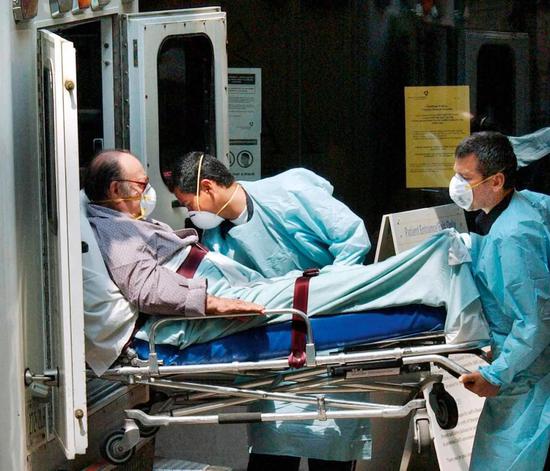 2003年6月11日，加拿大多伦多综合医院，两名穿着SARS防护服的医护人员从救护车上抬下一名病人