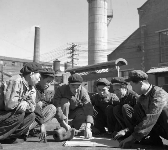  图为沈阳铸造厂开展科学普及工作，第二车间技术员、科普小组组员张玉生（右四）利用休息时间帮助工人学习看图（1956年10月24日发）。新华社记者 于肇 摄