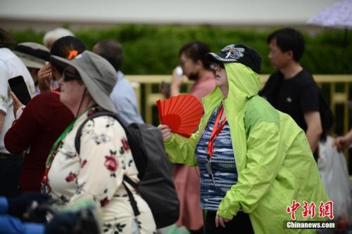  5月22日，在天安门前游玩的外国游客“花式”遮阳。 中新社记者 张兴龙 摄