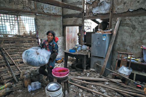  ▲昨日，双河镇，村民在破损的房间内整理物品，带走离开。