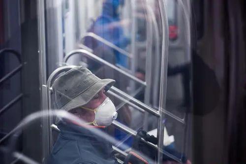 3月17日，美国纽约乘坐地铁里的一名乘客戴着口罩和手套。