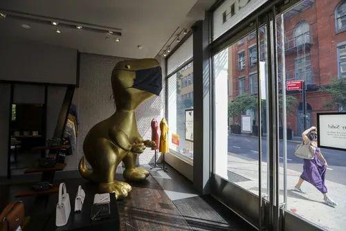 7月30日，在美国纽约苏豪商业区，一家商店内的恐龙雕像被“戴”上口罩。新华社记者王迎摄