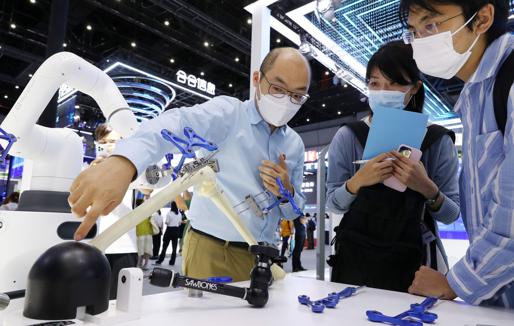 2022年9月1日，工作人员（左一）向参观者介绍微创骨科手术机器人。当日，2022世界人工智能大会在上海世博中心拉开帷幕。新华社记者 方喆 摄