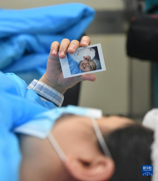 2020年6月1日，在湖北武汉，彭银华的妻子钟欣在看自己与女儿的合影。新华社发（王永胜 摄）