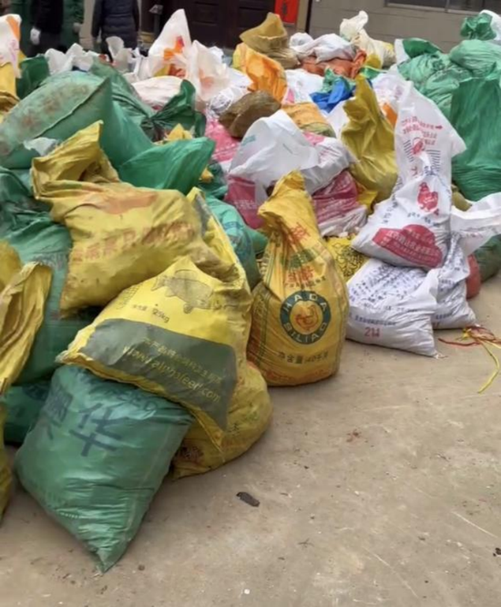 村民挖来的锂矿石装进饲料袋，堆在村庄空地上。