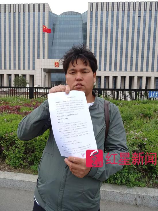  ▲去年5月23日，刘忠林在吉林省高院门前，手拿国家赔偿申请书    受访者供图