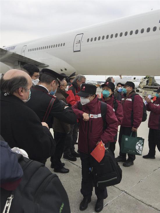 3月25日，在意大利米兰马尔奔萨机场，意方人员以“击肘”的方式欢迎中国第三批赴意大利抗疫医疗专家组成员的到来。新华社发