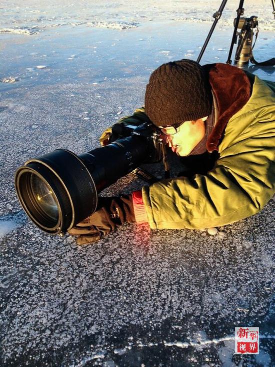  新华社记者吴刚趴在结冰的青海湖上拍摄。