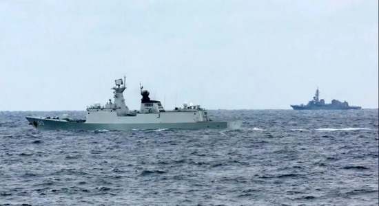 中俄海军首次海上联合巡航期间,日自卫队舰艇(右)对中方滨州舰(左)进行跟踪侦察(10月21日摄)。