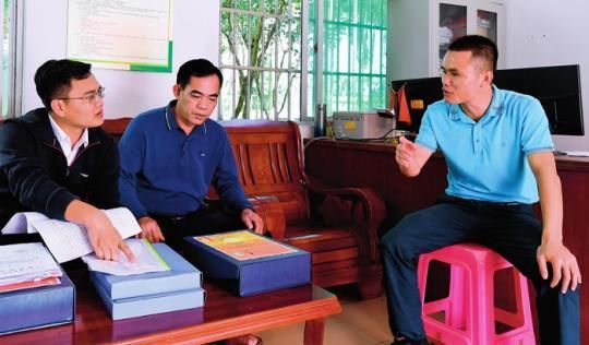 在海南省琼中黎族苗族自治县湾岭镇加章村委会，纪检监察干部（左一）在查阅乡村振兴及村级财务支出相关材料（2021 年 11 月13 日摄） 杨冠宇摄 / 本刊