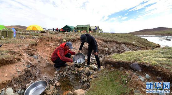 科研人员和后勤人员从营地前的小溪取生活用水（2017年6月24日摄）。新华社记者 晋美多吉 摄