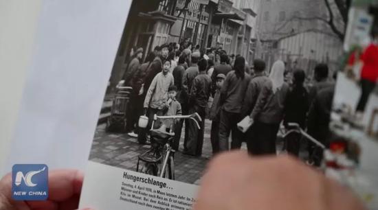 ▲库摩展示他1976年在中国拍摄的照片。(新华社报道截图)