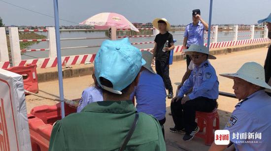 周素林(化名、绿衣戴帽者)在栏杆外围,希望能回家看看