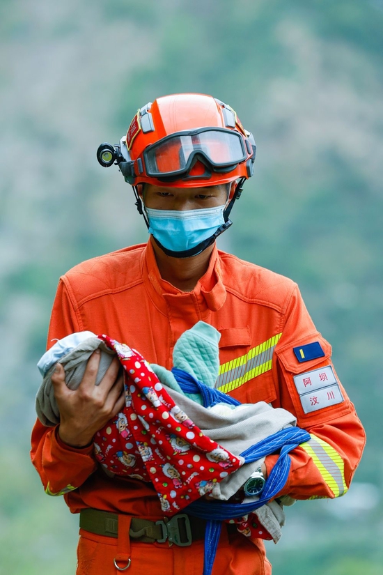 2022年9月6日，阿坝森林消防支队汶川大队队员张自立抱着一名从泸定县得妥镇湾东村疏散出来的2个月大的婴儿。新华社记者 沈伯韩 摄