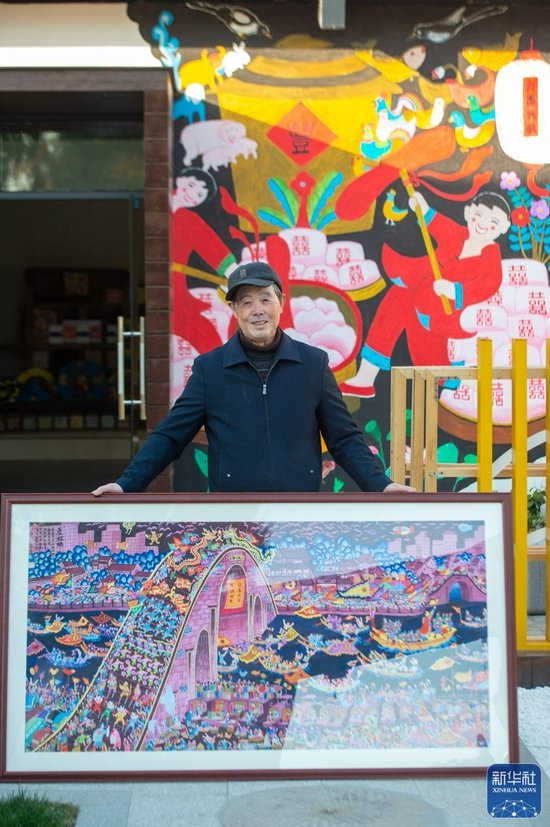 浙江省嘉兴市秀洲区油车港镇胜丰村村民张金泉与自己的画作《国泰民安》合影（2020年12月15日摄）。新华社记者 江汉 摄
