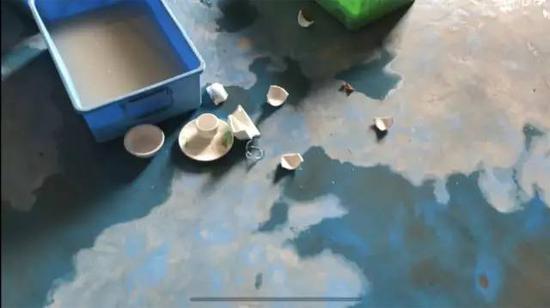 ▲人工清洗所用的水都已浑浊,地上散落着破碎的餐盘。 新京报记者 刘经宇 摄